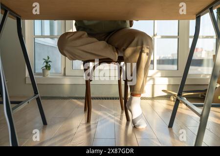 Homme assis sur une chaise à table à la maison Banque D'Images