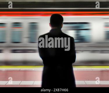 Homme debout devant un train de métro en mouvement Banque D'Images