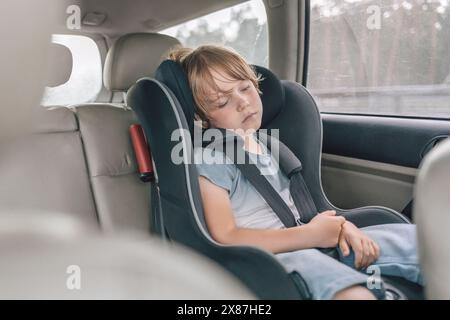 Garçon fatigué dormant sur un siège bébé dans la voiture Banque D'Images