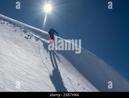 Skieur ski sur piste enneigée à la journée ensoleillée Banque D'Images