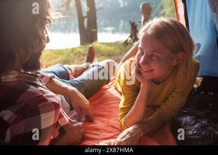 Femme souriante couchée à côté de petit ami dans la tente Banque D'Images