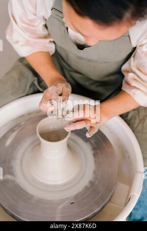Potier moulant de l'argile sur la roue de poterie au studio d'art. Banque D'Images