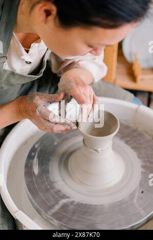 Artiste confiant moulant de l'argile sur la roue de poterie au studio d'art. Banque D'Images