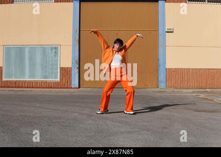 Femme confiante dansant avec les bras levés devant le bâtiment le jour ensoleillé Banque D'Images