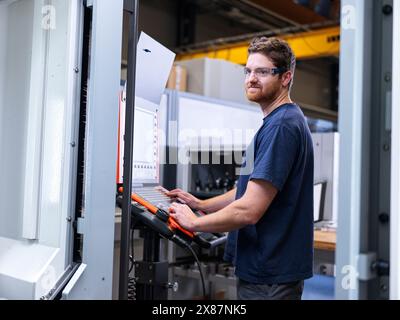 Apprenti ingénieur exploitant la machine CNC en usine Banque D'Images