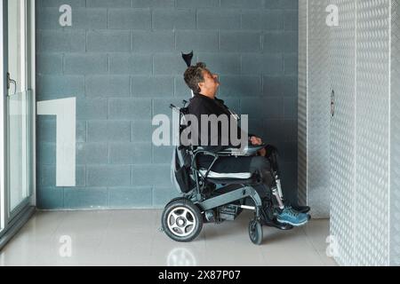 Homme âgé handicapé attendant l'ascenseur dans le couloir Banque D'Images