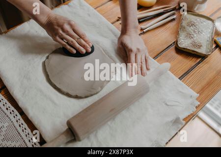 Mains de femme moulant de l'argile sur tissu blanc à la maison Banque D'Images