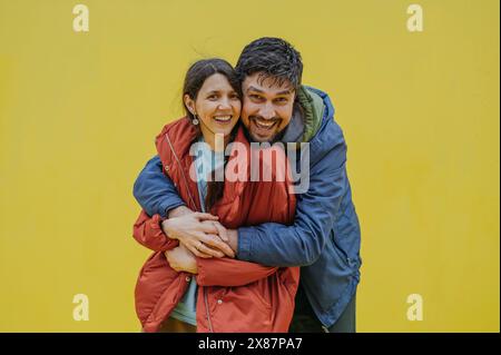 Homme mûr heureux embrassant la femme sur fond jaune Banque D'Images