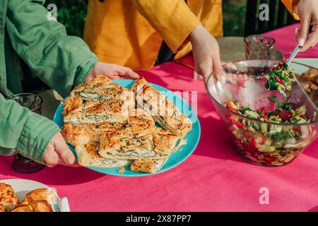 Mains de femmes servant de la salade verte et du pain farci au fromage à la table à manger Banque D'Images