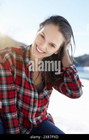 Heureuse belle femme portant une chemise à carreaux rouges à la plage Banque D'Images