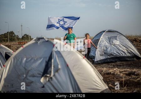 23 mai 2024, Israël, Kibboutz ami'ad : les Israéliens évacués des zones nord près de la frontière libanaise en raison des tensions transfrontalières continues, se tiennent debout au milieu de tentes lors d'un rassemblement appelant le gouvernement à les laisser rentrer chez eux. Photo : Ilia Yefimovich/dpa Banque D'Images