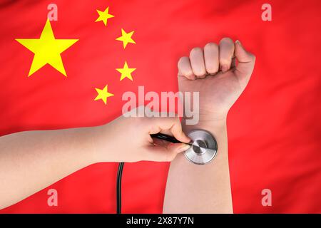 La tête d'un stéthoscope médical au poignet (gros plan) sur fond de drapeau chinois. Concept de système de santé chinois Banque D'Images