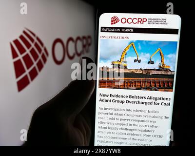 Personne tenant un téléphone cellulaire avec le site Web du projet de signalement du crime organisé et de la corruption (OCCRP) avec le logo. Concentrez-vous sur le centre de l'écran du téléphone. Banque D'Images