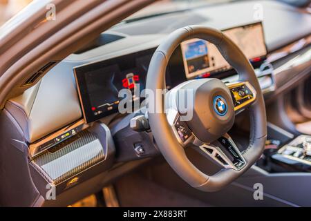 Vue rapprochée du volant et du tableau de bord garnis de fibre de carbone de la voiture électrique BMW i5-M. Banque D'Images