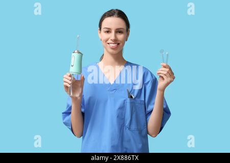 Femme dentiste avec irrigateur buccal sur fond bleu Banque D'Images