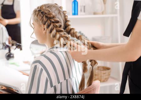 Coiffeur professionnel tressant les cheveux du client dans le salon Banque D'Images