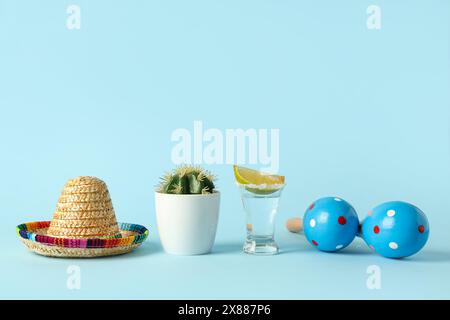 Cactus avec maracas mexicains, sombrero et tequila sur fond bleu. Cinco de Mayo Banque D'Images