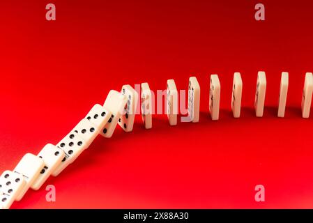 Effet domino agissant sur les pièces acryliques. Tombant sur un fond rouge. Banque D'Images