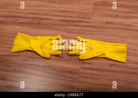 Paire de gants de nettoyage en caoutchouc jaune isolés sur fond de bois. Banque D'Images