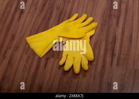 Paire de gants de nettoyage en caoutchouc jaune isolés sur fond de bois. Banque D'Images