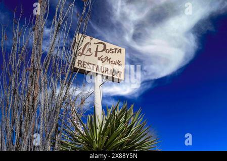 Signe au sommet du haut poteau pour le restaurant la Posta de Mesilla parmi les plantes Yucca et les cactus octillio avec un ciel et des nuages spectaculaires à Mesilla, NM, États-Unis Banque D'Images