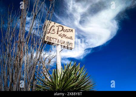 Signe au sommet du haut poteau pour le restaurant la Posta de Mesilla parmi les plantes Yucca et les cactus octillio avec un ciel et des nuages spectaculaires à Mesilla, NM, États-Unis Banque D'Images