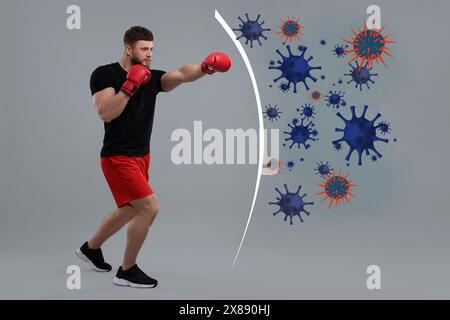 Homme sportif avec des gants de boxe s'exerçant sur fond gris. Immunité forte aidant à lutter contre les virus Banque D'Images