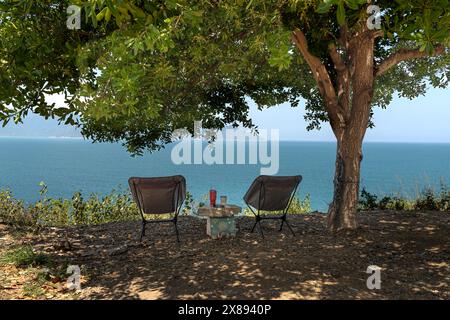 Nha Trang City, Vietnam - 30 mars 2024 : femme se reposant à l'ombre d'un arbre regardant vers la mer. Concept de relaxation Banque D'Images