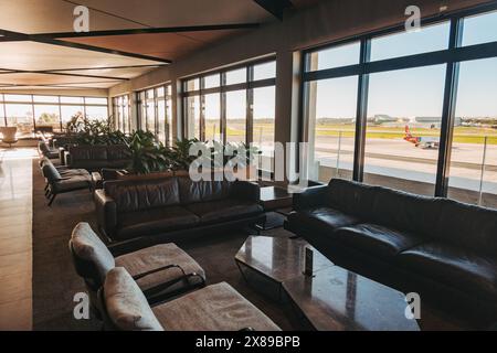 Le salon la Valette Club de l'aéroport international de Malte présente un intérieur moderne avec vue panoramique sur la piste et des éléments décoratifs en bois Banque D'Images