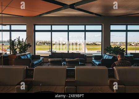 Le salon la Valette Club de l'aéroport international de Malte présente un intérieur moderne avec vue panoramique sur la piste et des éléments décoratifs en bois Banque D'Images