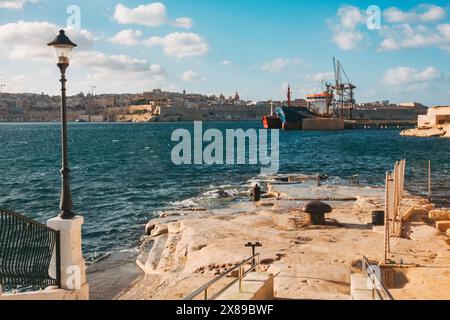 Cale de Rinella et plage de chiens à Kalkara, Malte. Un rocher bas qui tombe dans la mer Banque D'Images