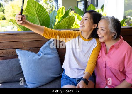 À la maison, mère asiatique d'âge moyen et jeune fille adulte prenant selfie Banque D'Images