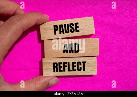 Arrêtez-vous et réfléchissez les mots écrits sur des blocs de bois avec un fond rose. Symbole conceptuel de pause et de reflet. Banque D'Images