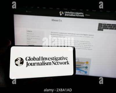 Personne tenant un smartphone avec le logo du Global Investigative Journalism Network (GIJN) devant le site Web. Concentrez-vous sur l'affichage du téléphone. Banque D'Images