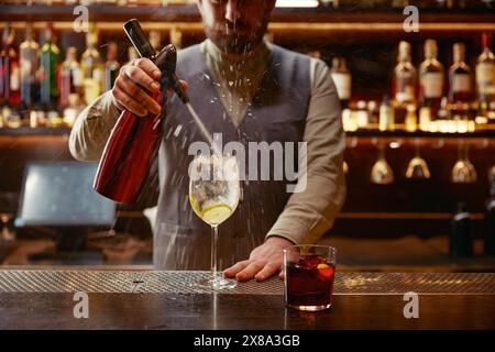 Barman préparant un cocktail frais debout dans un jet de liquide volant Banque D'Images