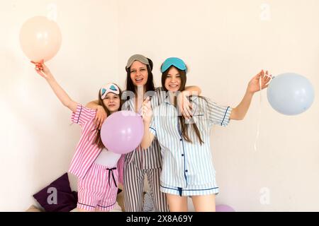 Famille s'amuser avec des ballons en pyjama rayé à la maison. Maman et deux dauthers. Chambre Balloon Pajama Party Banque D'Images