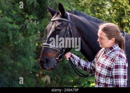 Femme tenant un cheval bridé dehors. Portrait d'un cavalier et d'un cheval Banque D'Images