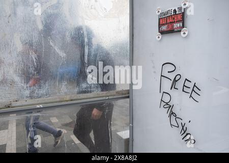 Graffiti et affiche gratuits pour la Palestine dans un abri de bus à Dumfries, en Écosse, un jour de pluie avec des gens qui passent devant. Banque D'Images