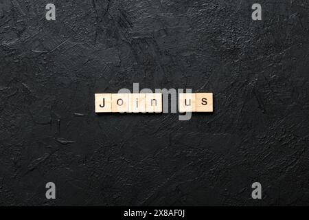 Joignez-vous à nous mot écrit sur le bloc de bois. Joignez-vous à nous texte sur la table de ciment pour votre conception, vue de dessus. Banque D'Images