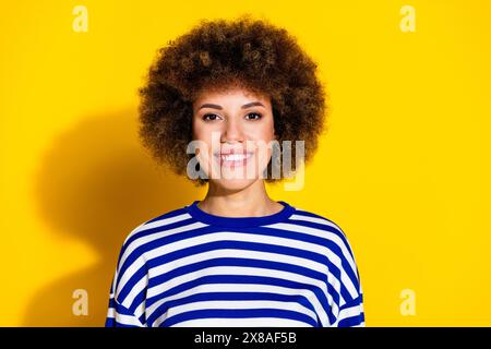 Photo de belle jeune fille rayonnante sourire vide chemise rayée isolée sur fond de couleur jaune Banque D'Images