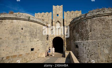 Emery d'Amboise Tor, enceinte de Rhodes, château médiéval avec porte en pierre massive et tours rondes, sous le ciel bleu, visiteurs au premier plan, Rhodes o Banque D'Images