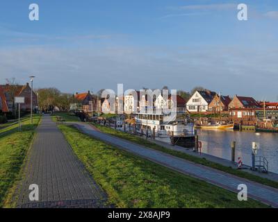 Un chemin pavé le long d'un canal avec des bateaux garés et des bâtiments de l'autre côté de l'eau, port historique avec des bâtiments anciens et de nombreux bateaux de pêche Banque D'Images