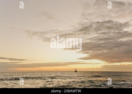Bateau navigue le soir au coucher du soleil illuminé sur l'île tropicale hawaïenne Banque D'Images