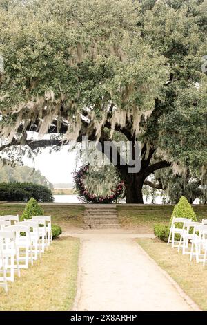 Configuration de cérémonie de mariage en plein air sous un grand arbre avec arc floral Banque D'Images