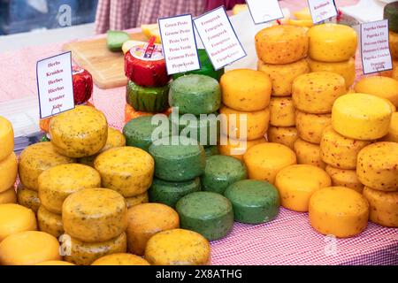 Divers fromages ronds affichés sur une table avec des indications dans différentes langues. Banque D'Images