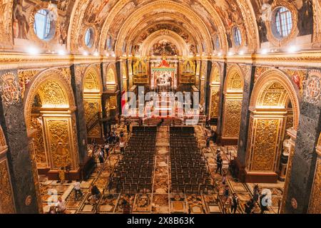 Vue de. John's Co-Cathedral balcon à la Valette, Malte, avec intérieur orné, sol carrelé, chaises, et visiteurs Banque D'Images