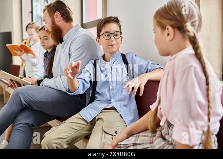 Un enseignant de sexe masculin instruit un groupe d'enfants divers dans une salle de classe lumineuse et animée, assis à proximité les uns des autres et absorbés par l'apprentissage. Banque D'Images
