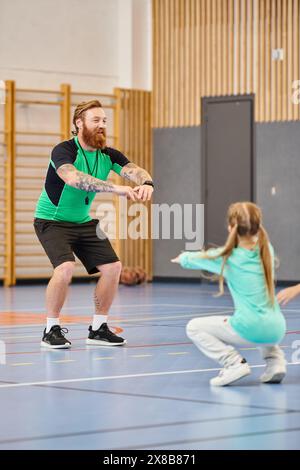 Un homme et une petite fille sont immergés dans la classe d'éducation physique dans le gymnase scolaire Banque D'Images