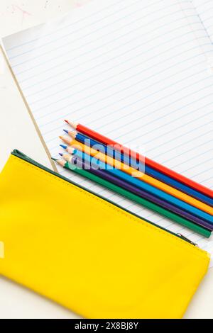 À l'école, des crayons de couleur reposant sur le dessus de la trousse jaune avec un espace de copie dans la salle de classe Banque D'Images