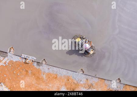 Dès que la fondation a été coulée avec du béton, les ouvriers l'ont nivelée à l'aide de machines à polir le béton Banque D'Images